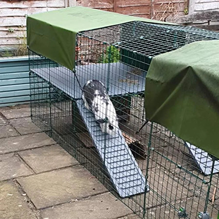 Green tarpaulin cover draped over wire animal cages outdoors