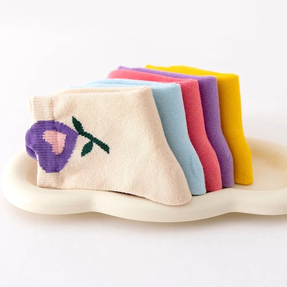 Folded girls crew socks stack: cream with purple flower, plus light blue, pink, purple, yellow
