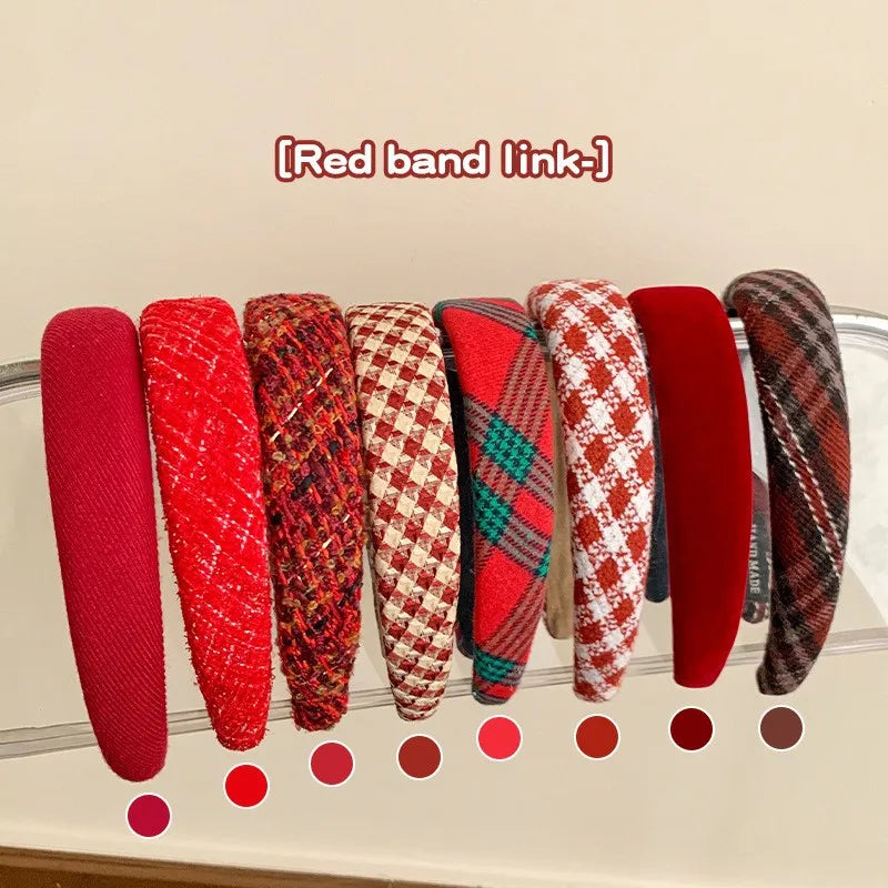 Assorted red fabric hair headbands with plaid and solid wide bands on display.
