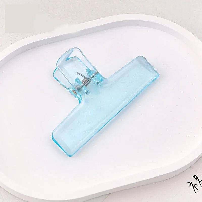 Blue ice jelly clip with transparent acrylic body and spring clasp on white tray
