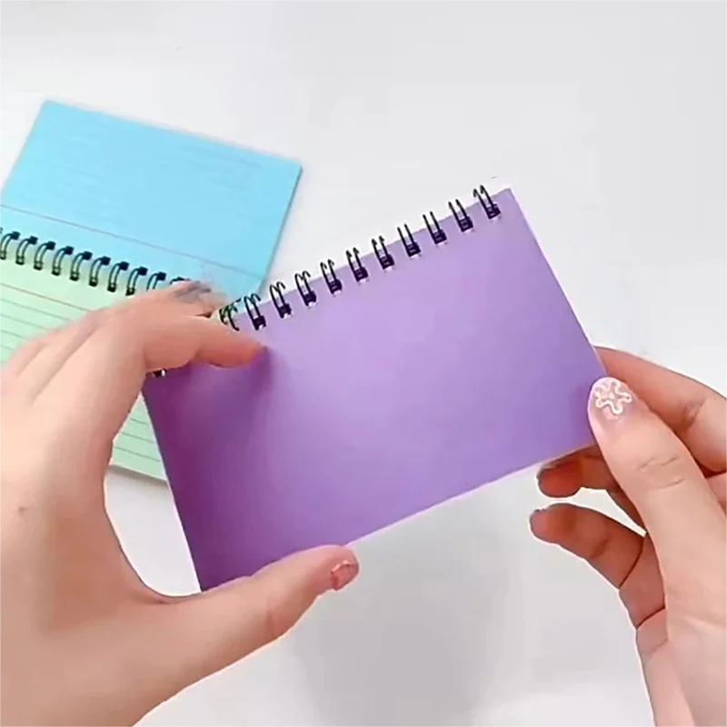 A5 lined spiral notebook held open with purple cover and black coil binding