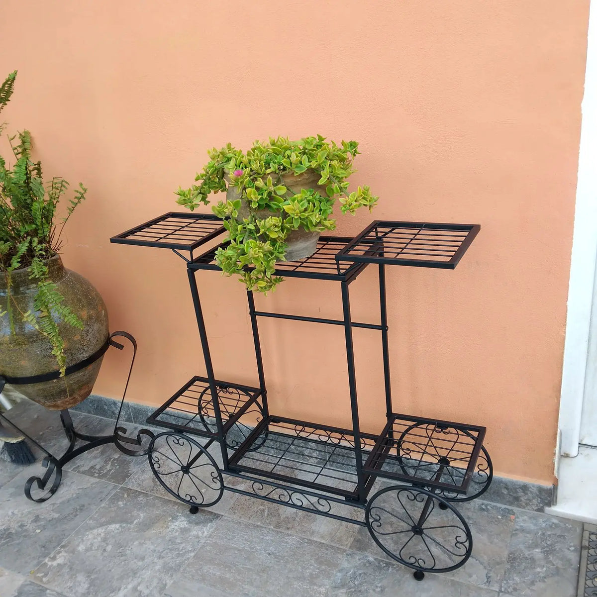 Black plant pot rack on wheels with two top shelves and lower side platform