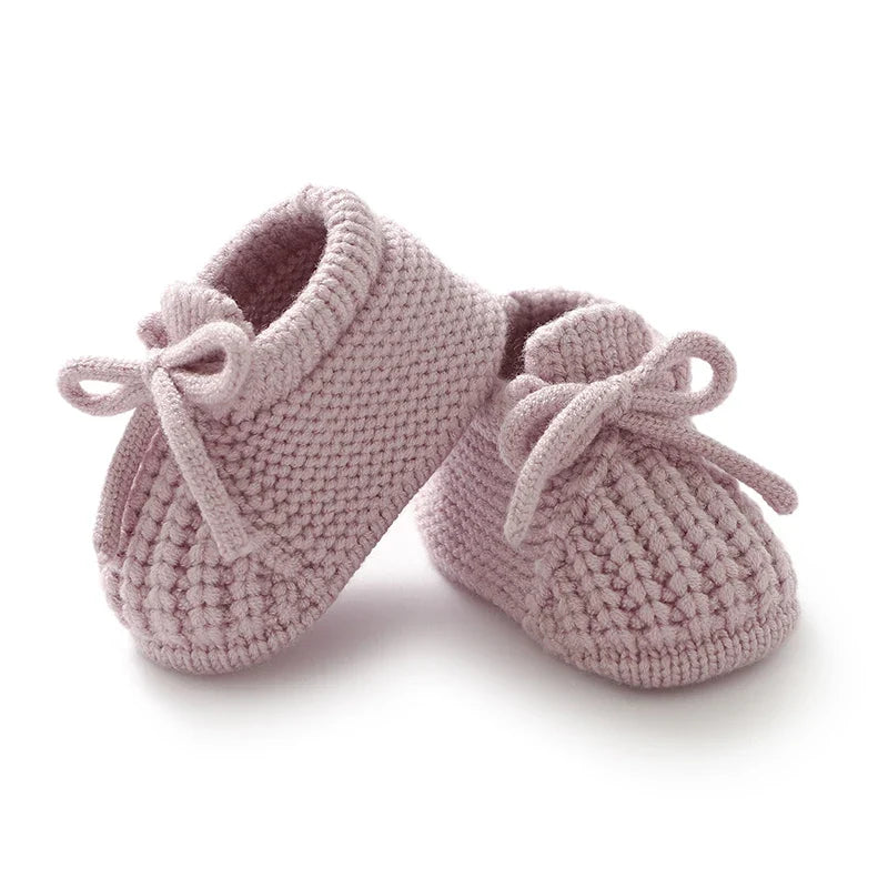 Mauve knitted baby booties with bow ties and ribbed cuffs