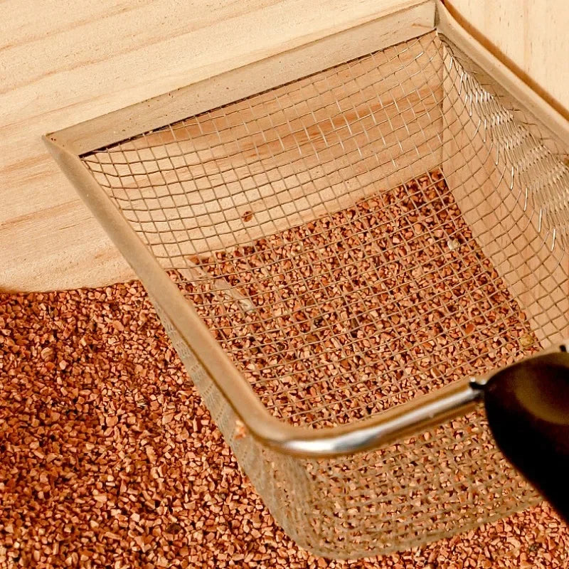 Stainless steel fine mesh sifting scoop with black handle, filled with substrate