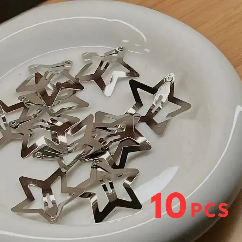 Silver star snap hair clips in a white dish, shiny star pieces with metal loops.