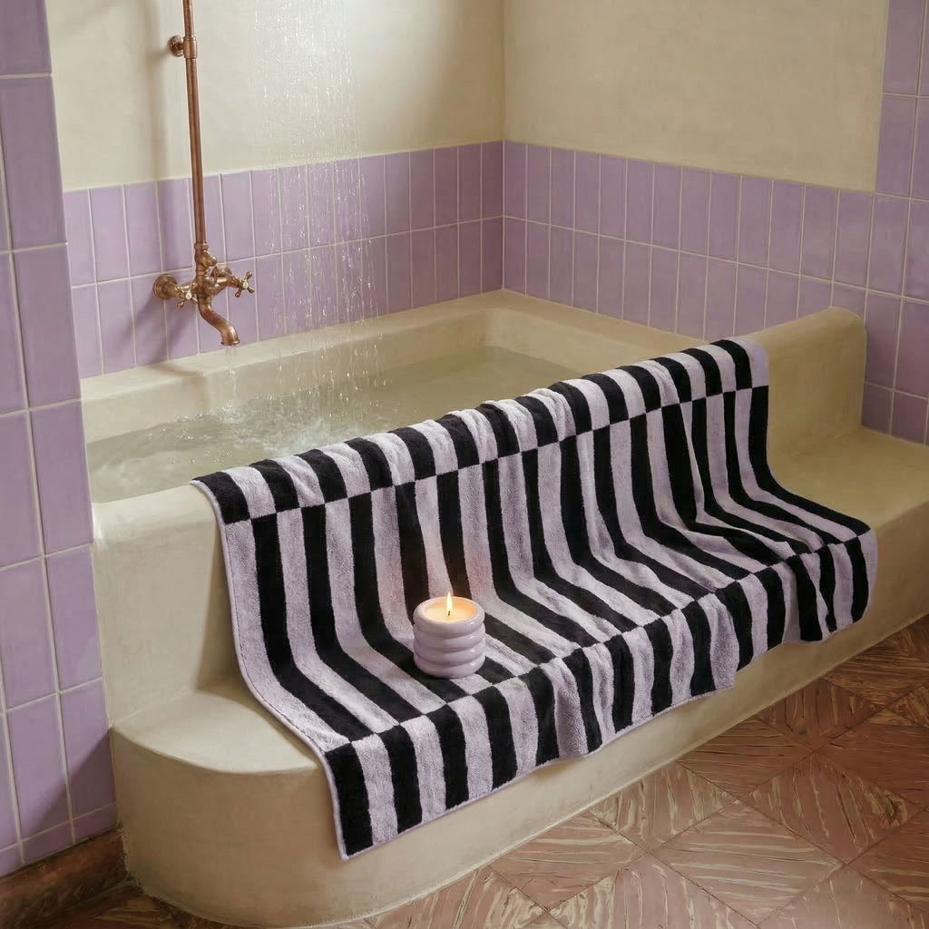 Black and white striped bath towel folded across a bathtub