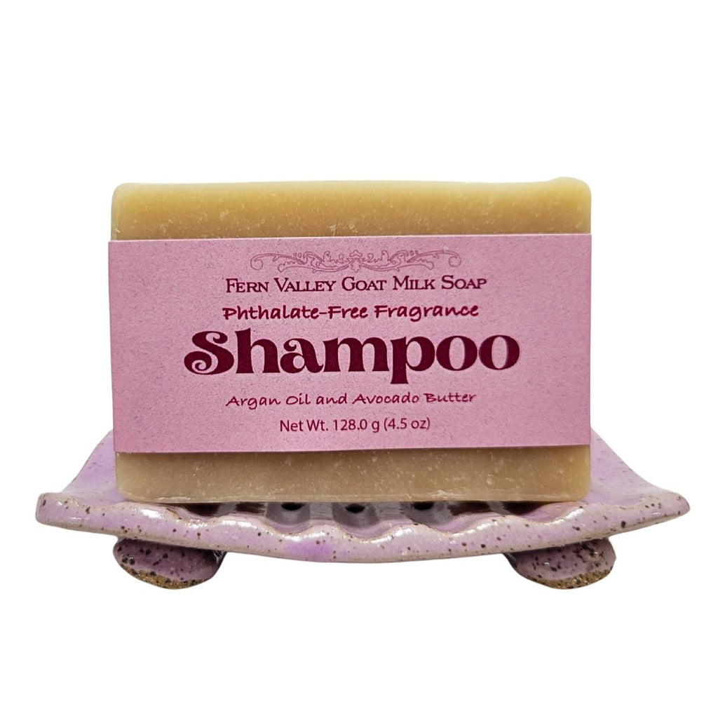 Handmade shampoo soap bar with pink label on a purple speckled dish, tan top bar