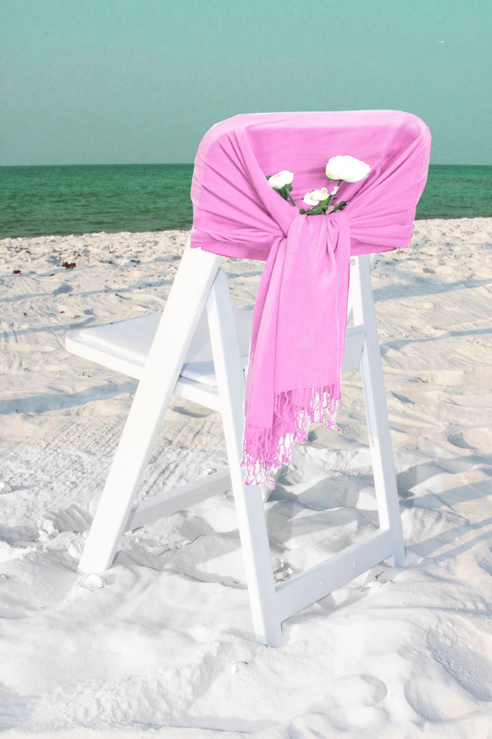 Bright pink pashmina-style shawl wrap scarf with fringe ends, draped over chair.