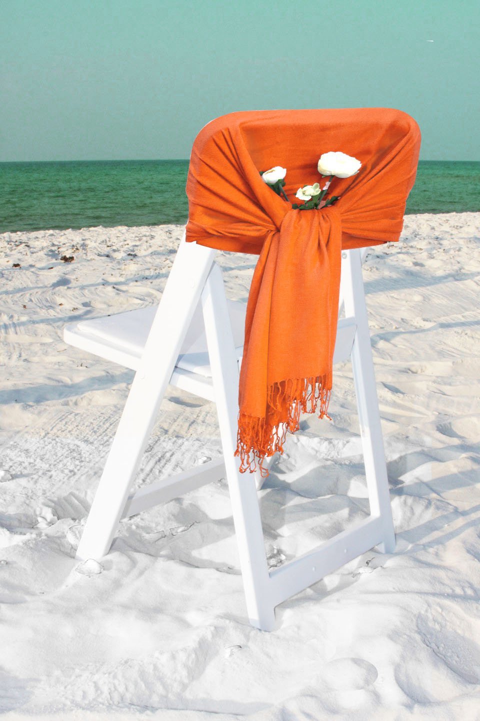 Orange pashmina-feel shawl scarf draped over chair back, fringed ends visible
