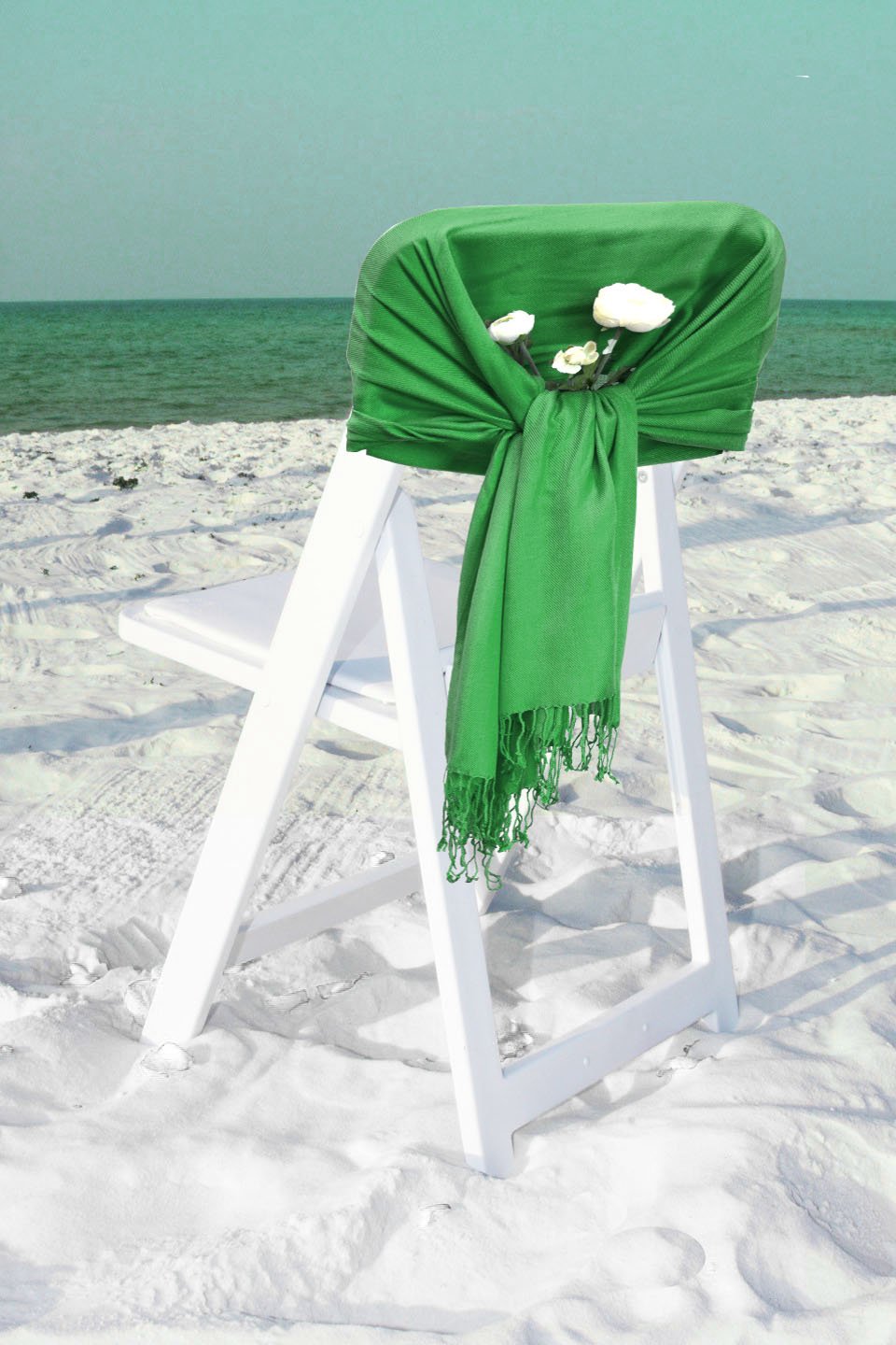 Solid green pashmina-style shawl wrap scarf with fringe hem, draped over chair