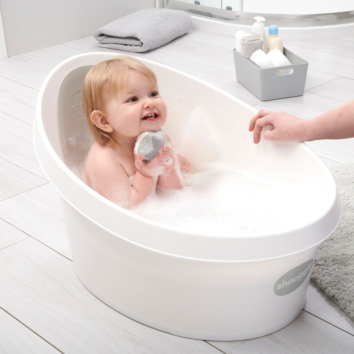 Toddler bath tub with white backrest, child sitting in soapy water