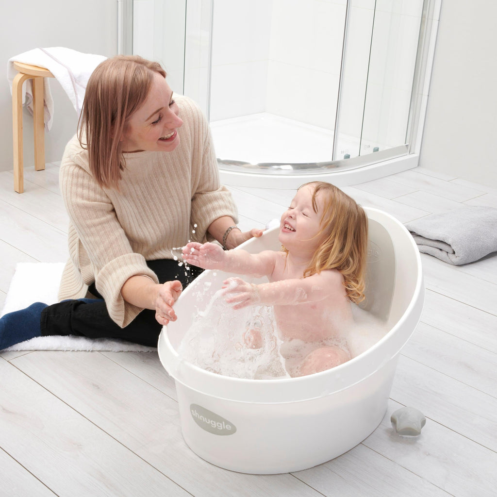 Toddler bath tub with white backrest support, child being bathed with bubbles