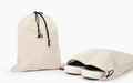 Beige canvas drawstring storage bag with sneakers inside, plus one folded bag
