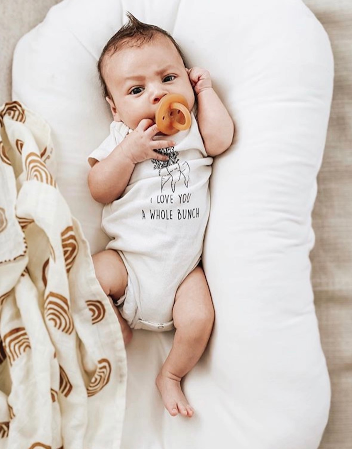 White baby bodysuit on infant with front figures-and-tree quote graphic.