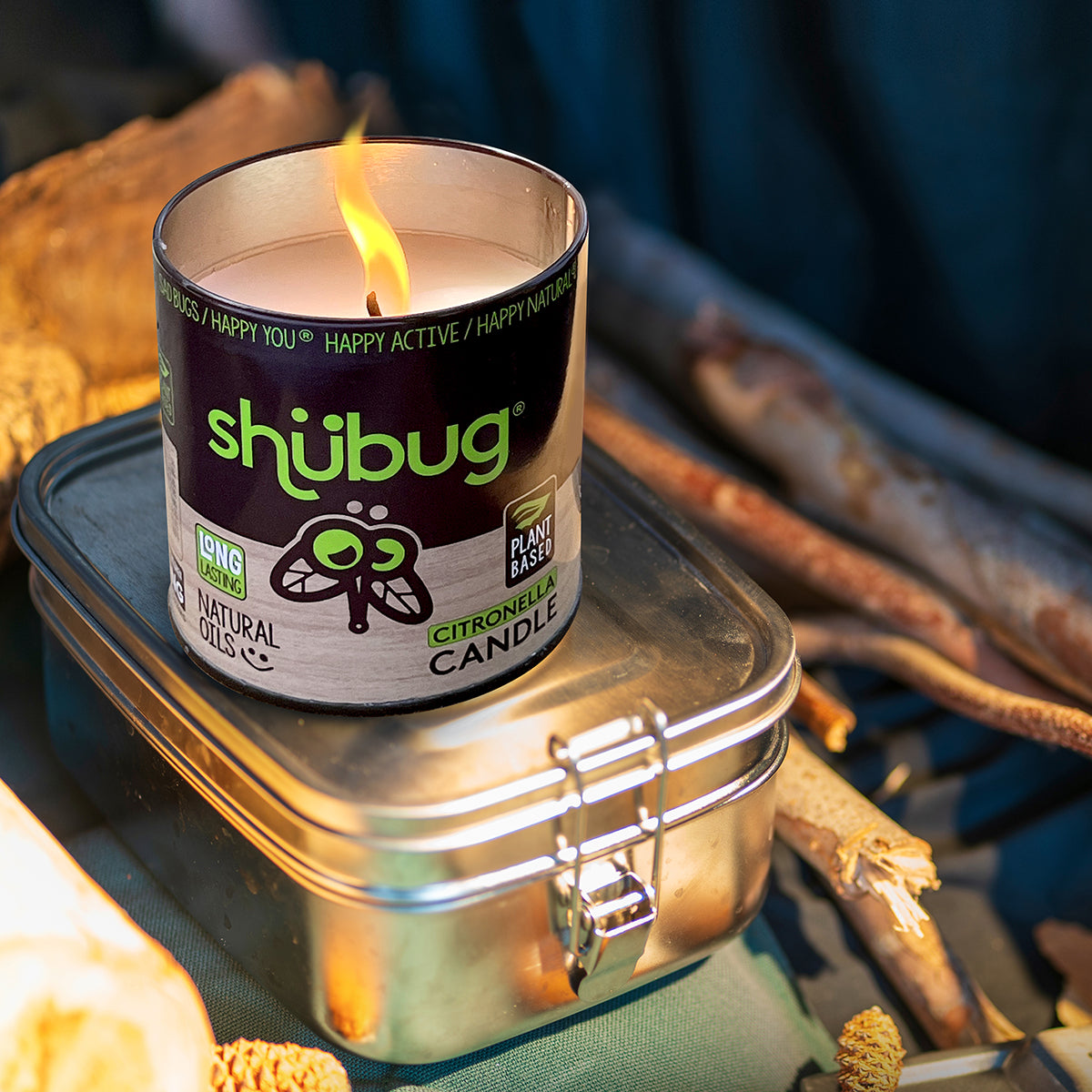 Burning Shubug citronella candle in metal tin with visible flame