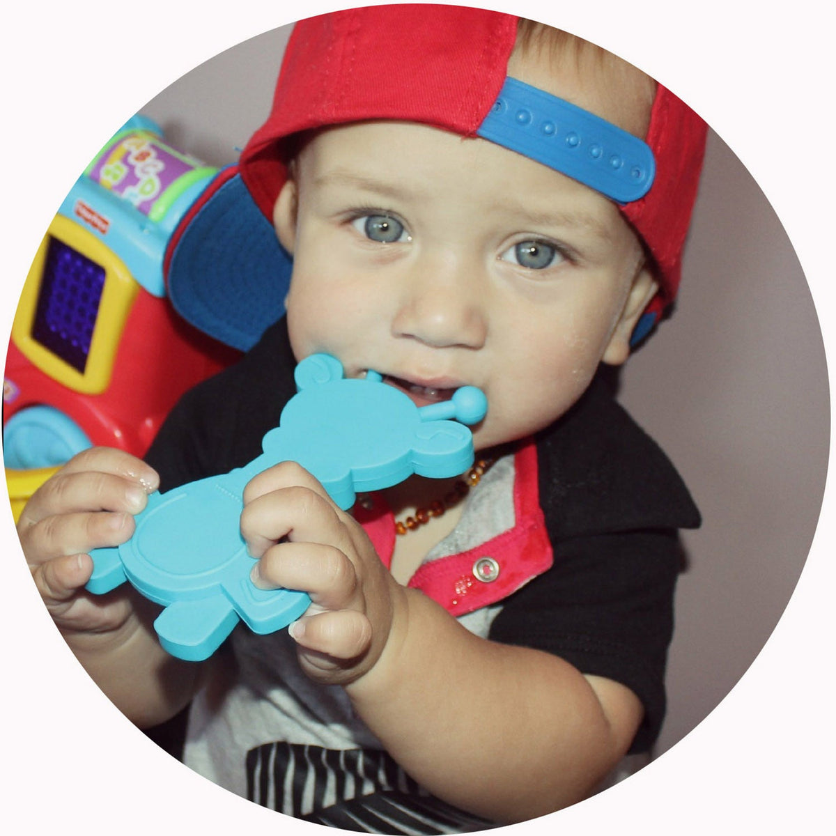 Baby chewing on a cyan giraffe teether with molded nubs
