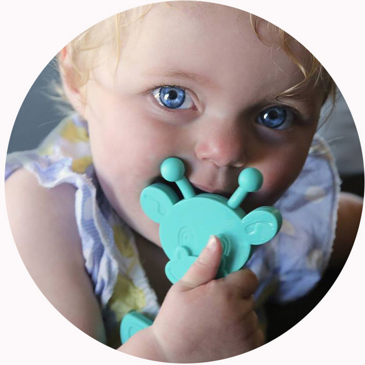 Turquoise bear-shaped teething toy in a baby’s hands for chewing
