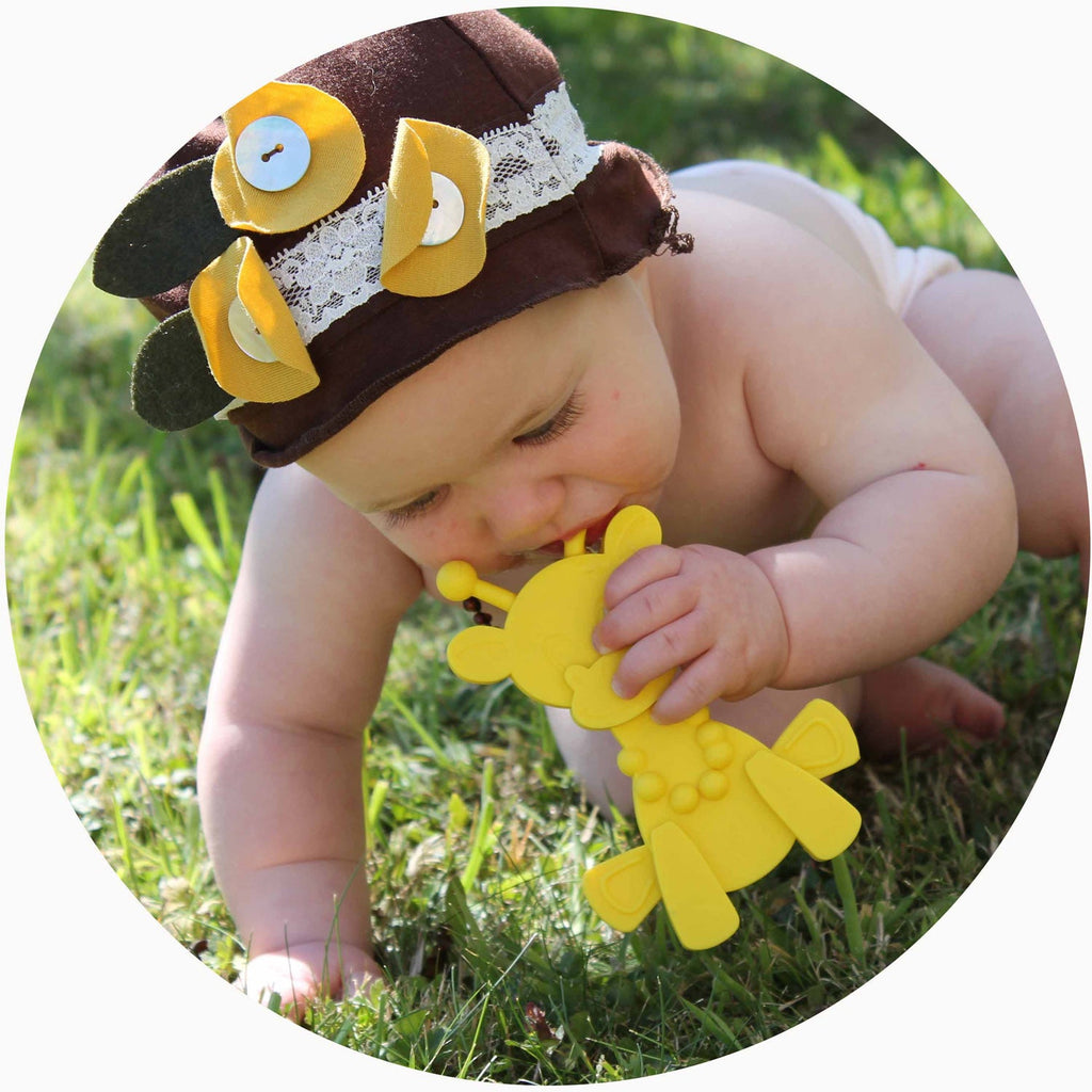 Baby playing with a yellow giraffe teething toy with raised, chewable textures