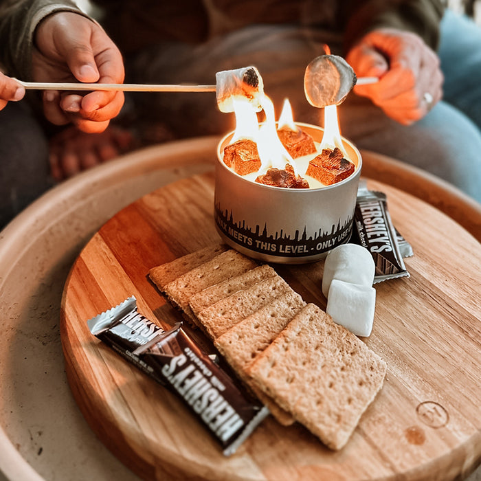Marshmallow roasting over flame in a s'mores fire pot with graham crackers