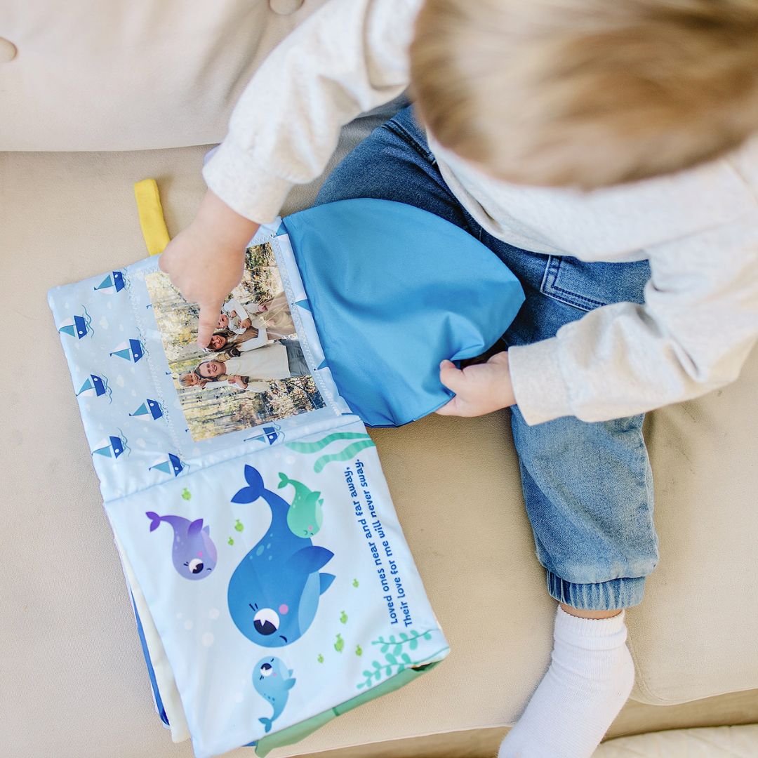 Baby using a blue photo-pocket storybook album with whale art and photo insert