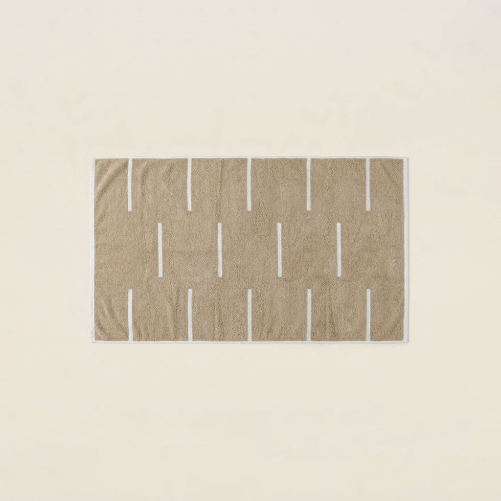 Tan towel with repeating ecru vertical bar pattern and textured loop weave.