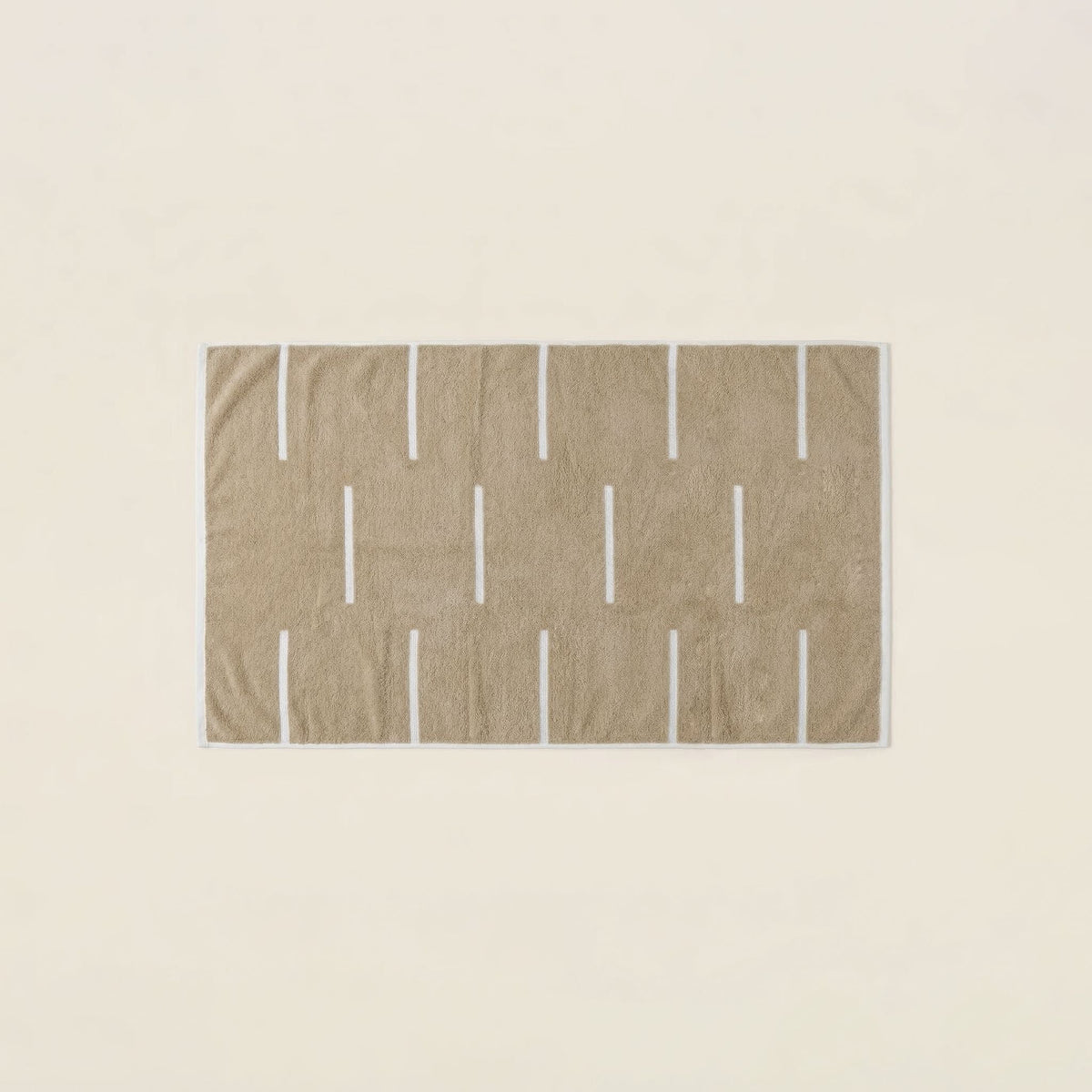 Tan towel with repeating ecru vertical bar pattern and textured loop weave.