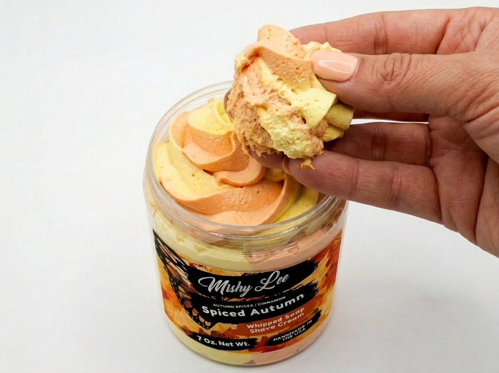 Hand holding a scoop of whipped cream soap in soft orange and cream swirls