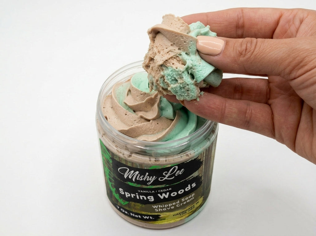 Hand holding a scoop of mint and beige whipped soap from the Mishy Lee jar