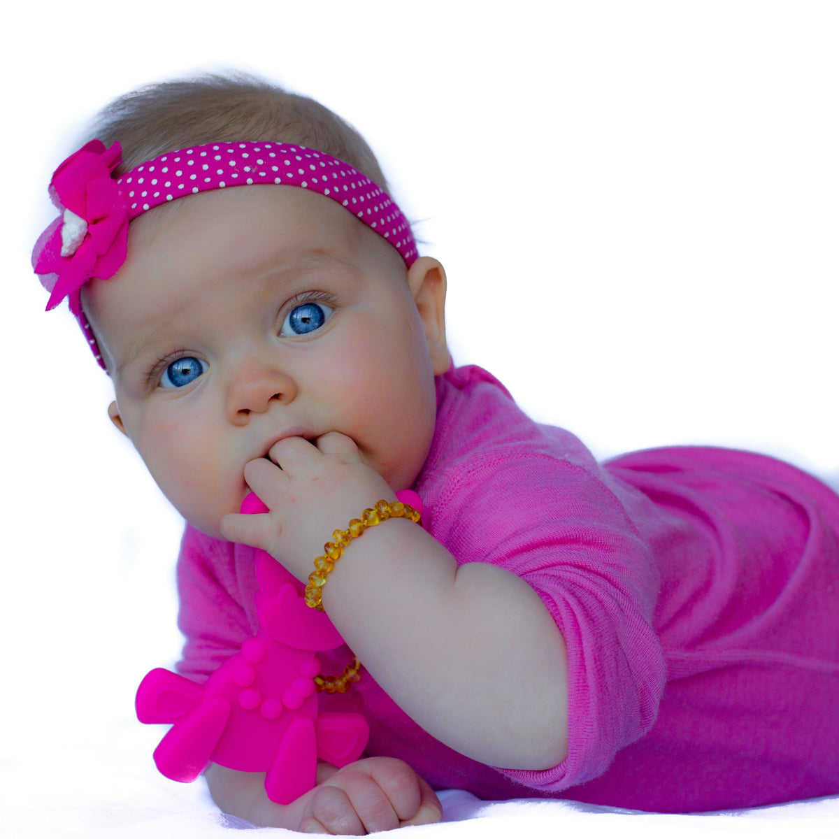 Magenta baby teething toy near baby's mouth with head-shaped textured bumps