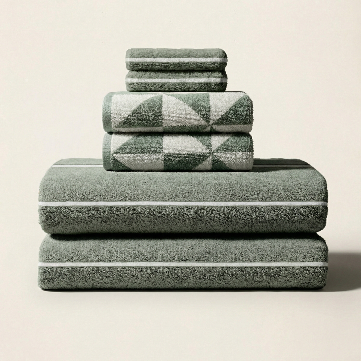 Stack of sage green and ecru geometric cotton towels with solid terry layers