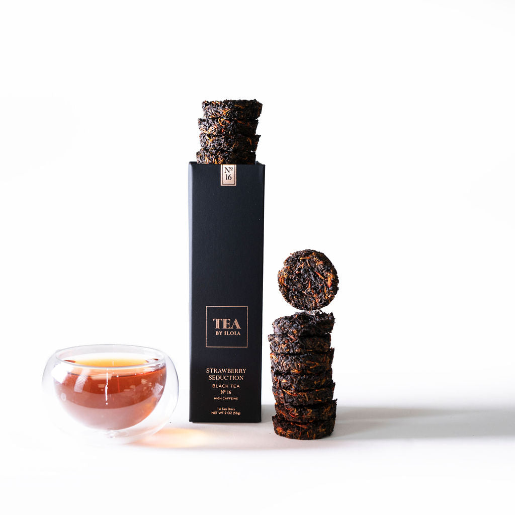 Strawberry Seduction tea box and stacked tea discs beside a cup of brewed tea