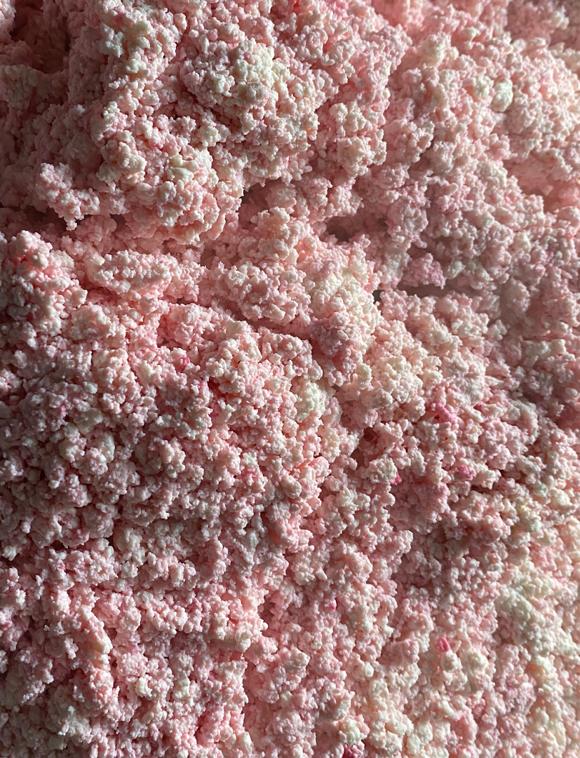 Pinkish crumbly cheese texture, fine granules close-up