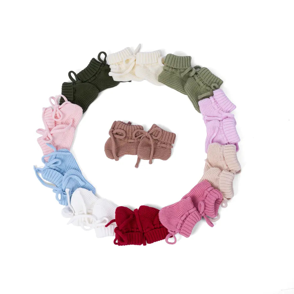 Knitted baby booties wreath display with rose pink booties and laces