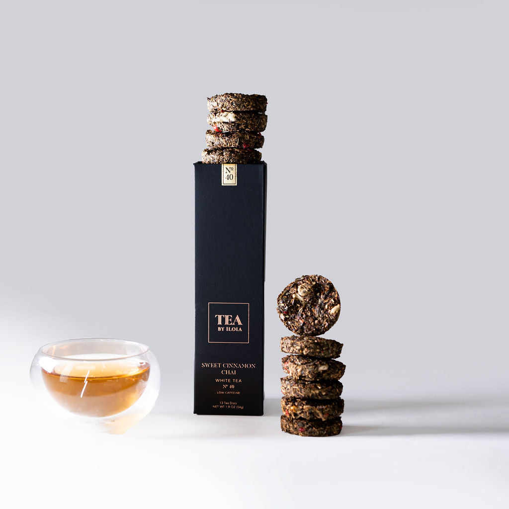 Black tea box, loose stacked tea discs, and a cup of brewed tea