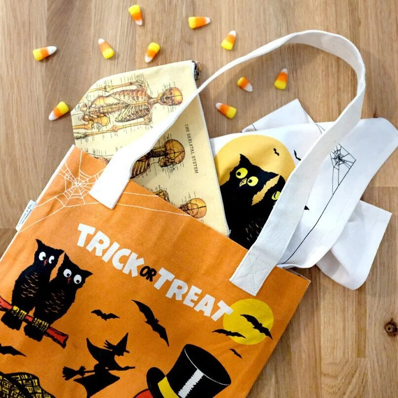 Orange Halloween canvas tote bag with “TRICK OR TREAT” graphic, shown with other tote bags