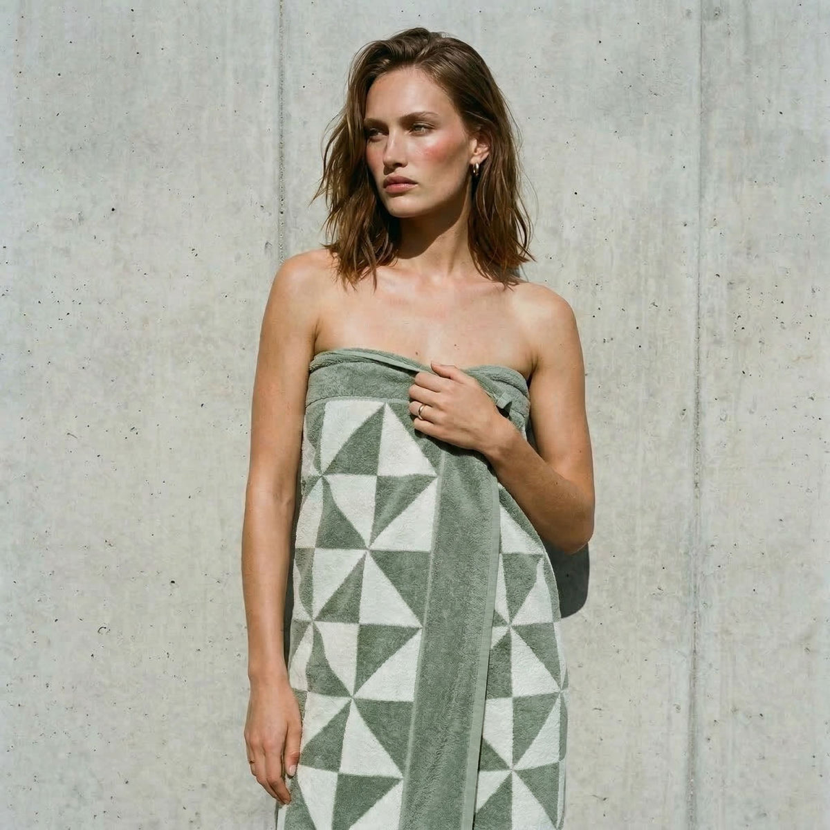 Sage green and ecru geometric-pattern cotton towel draped over shoulders