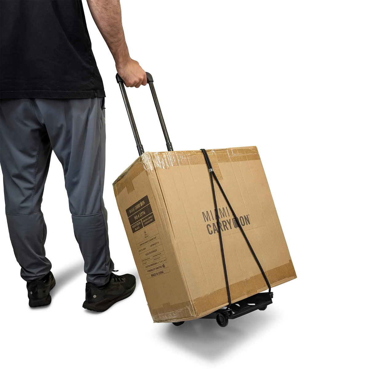 Folding luggage cart dolly pulling a cardboard box with telescoping handle