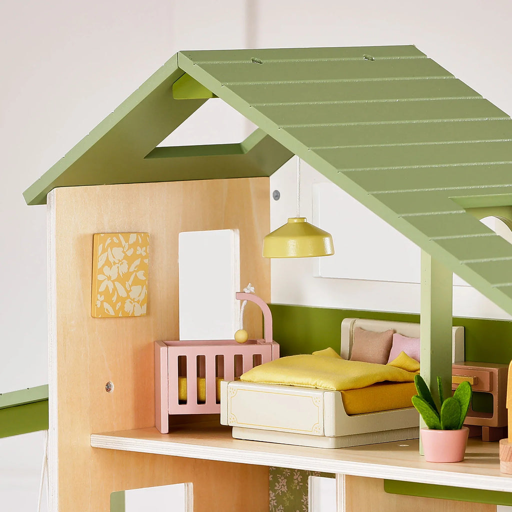 Close-up of green dollhouse interior with yellow bed, chairs, and potted plants