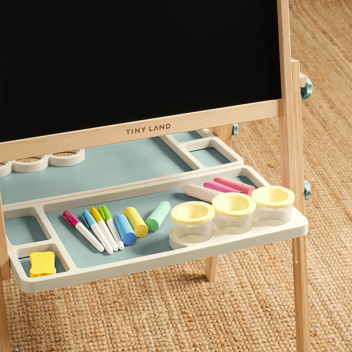 Close-up of easel tray with colored markers and white magnetic cups