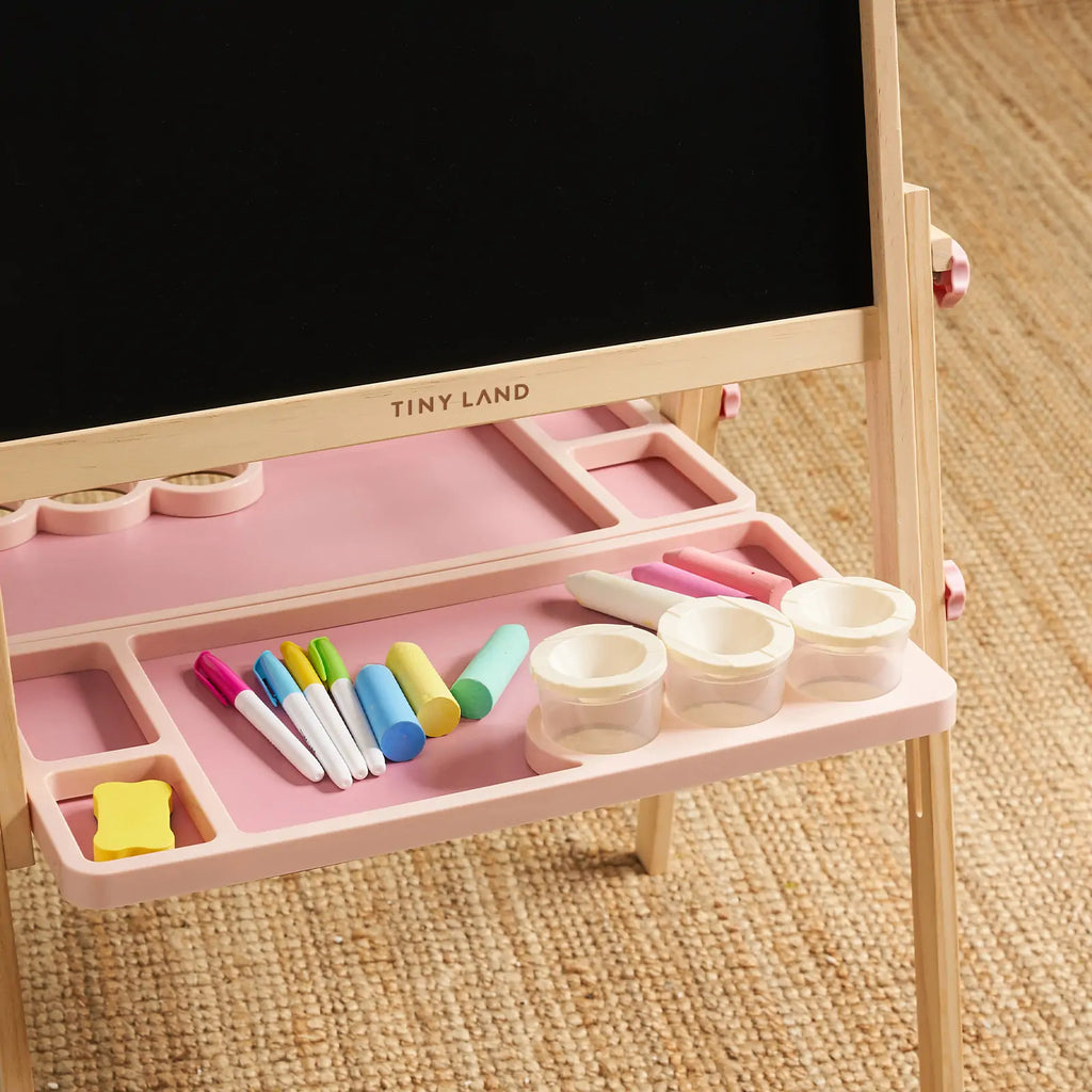 Pink easel base tray with colored markers and round paint pots