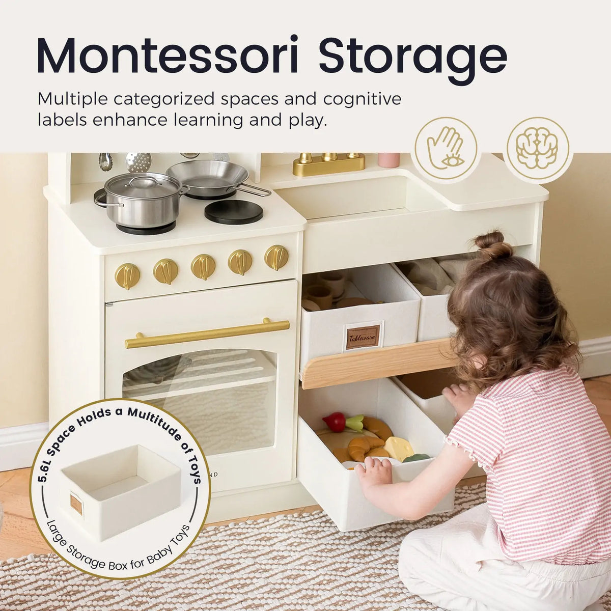 Wooden play kitchen with labeled storage shelves and toy pots, cream with gold hardware