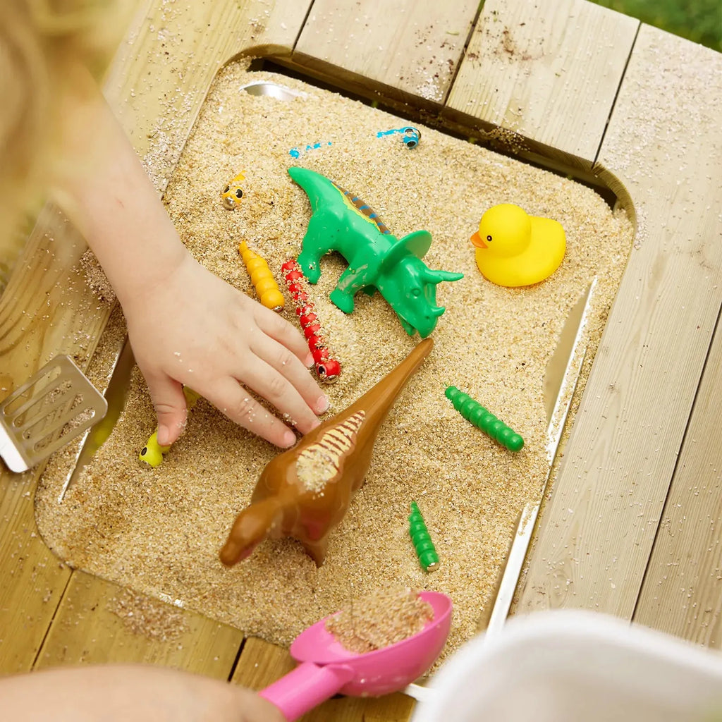 Hands playing with molded animal toys in sand tray of kids mud kitchen playset