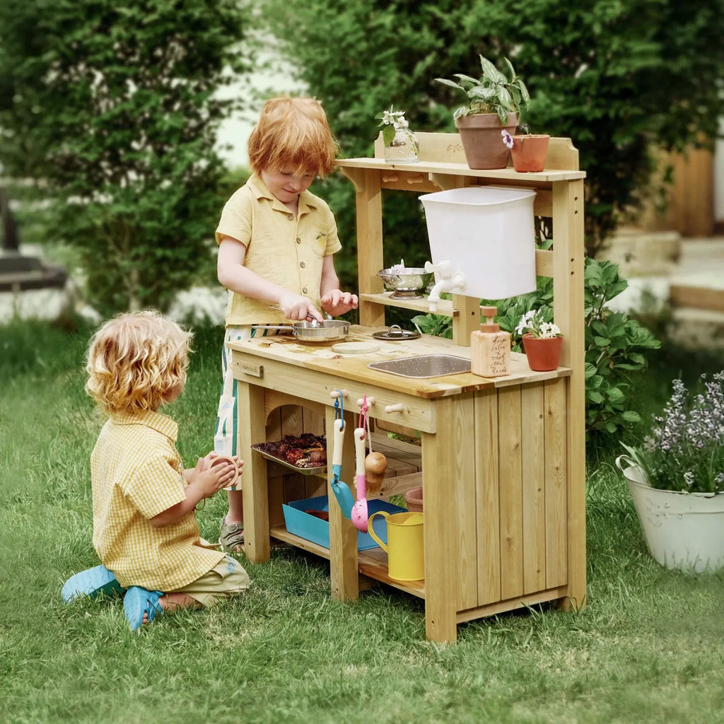 Kids using wooden mud kitchen playset outdoors with water bin and kitchen accessories