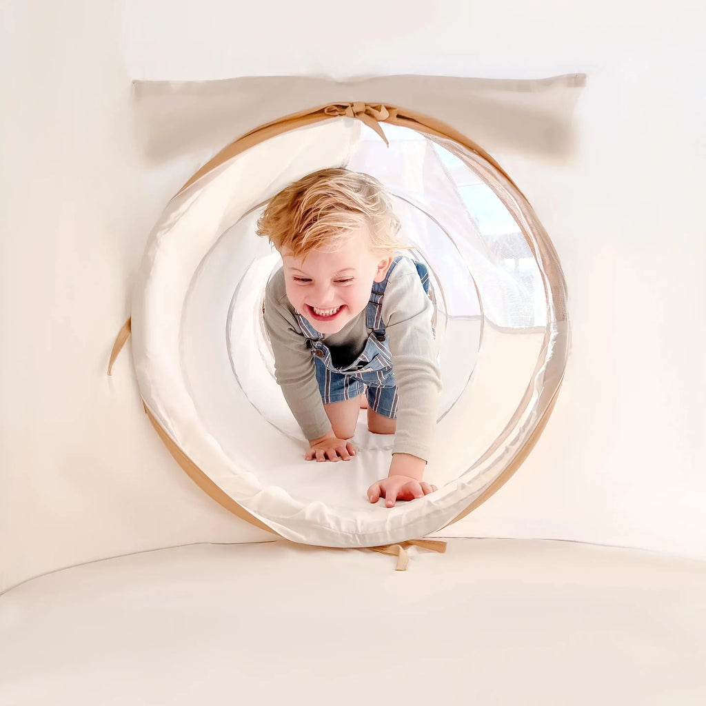 Soft play tunnel ring with star-pattern fabric, child crawling inside, beige and white