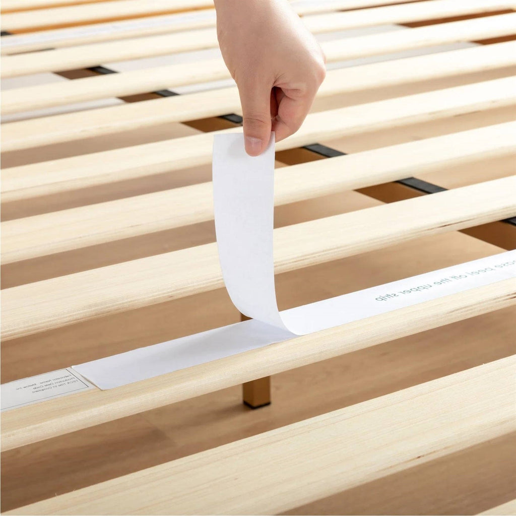 Wood platform bed slats with a fabric fastening strip being peeled back
