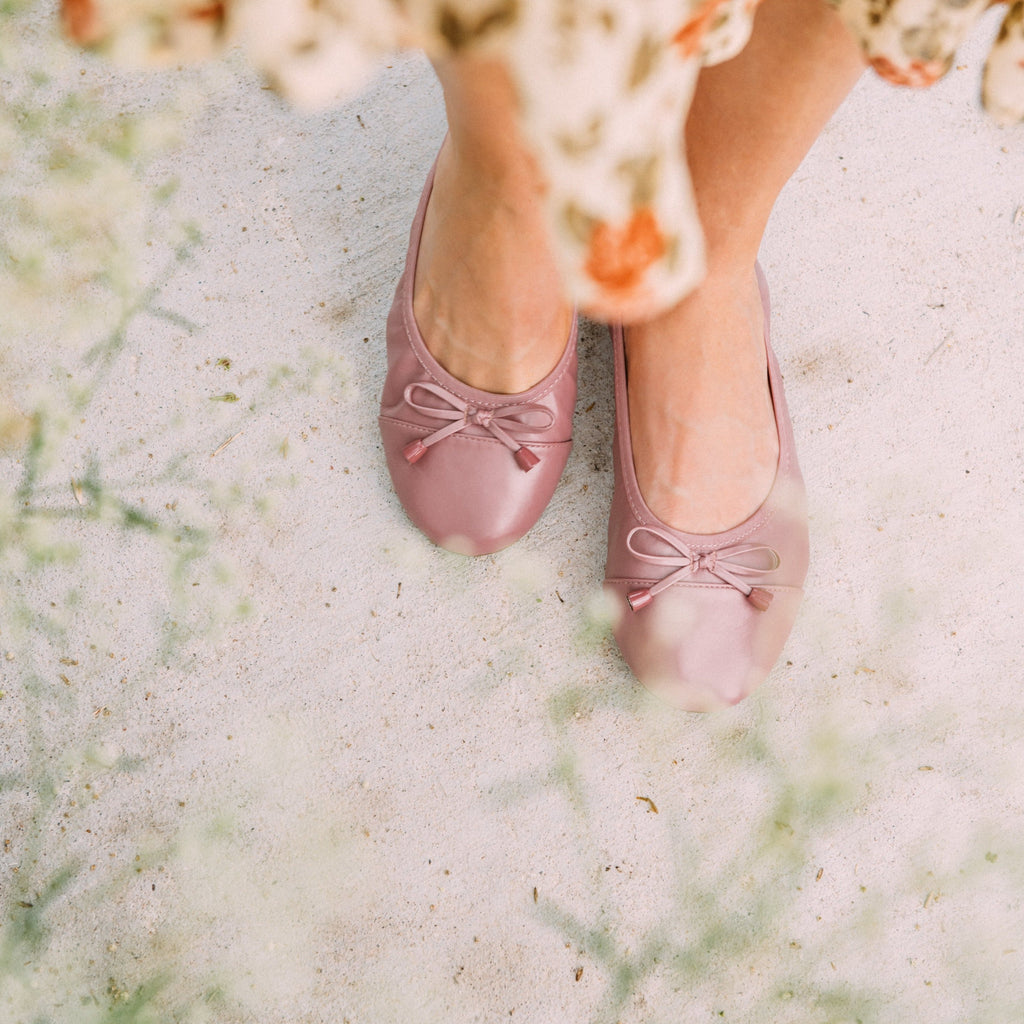 Dusty rose ballet flats on feet outdoors, tied bow detail