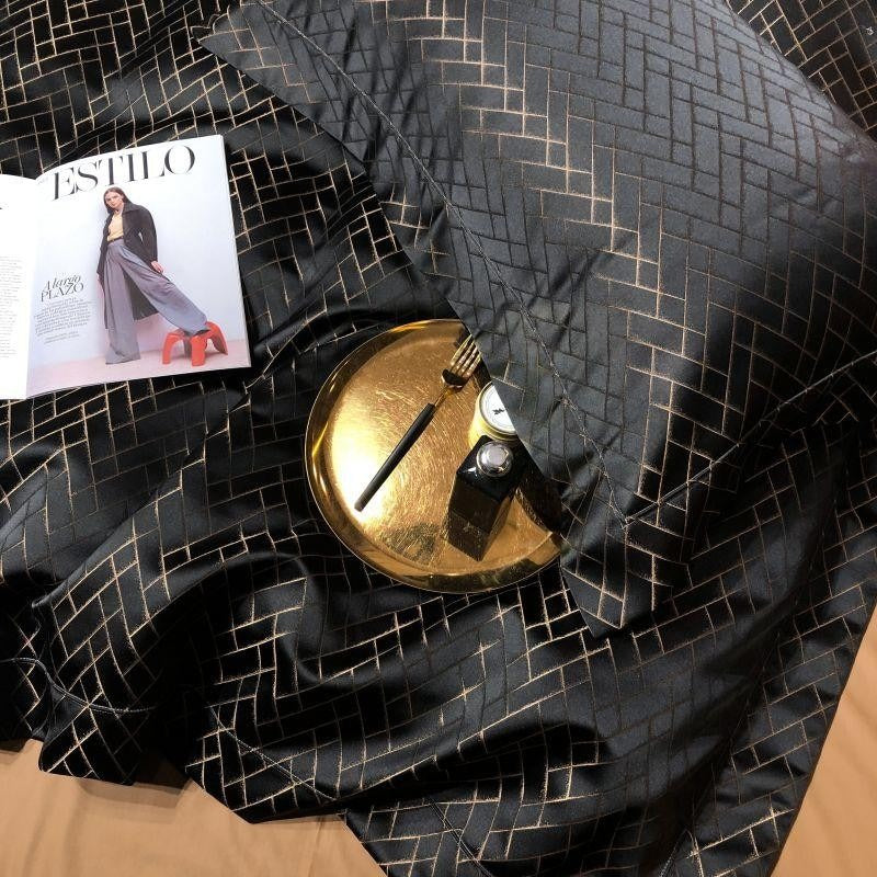 Black cotton satin duvet with gold geometric grid pattern; flat sheet and decor details