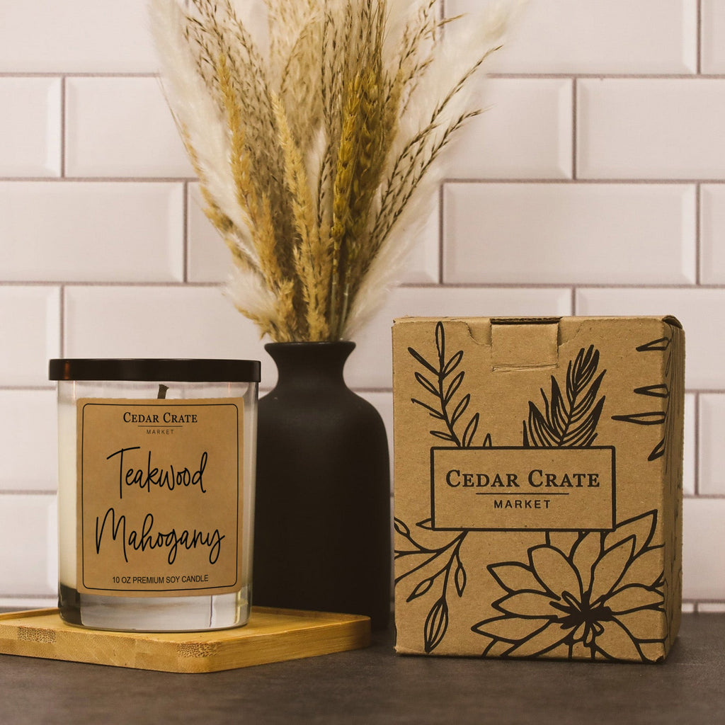 Teakwood Mahogany soy candle with black lid, shown beside kraft gift box and bag