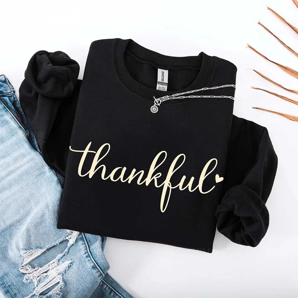 Black crewneck sweatshirt with “thankful” script print and chain charm detail at collar