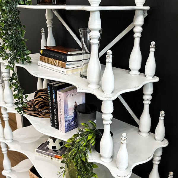 Close-up of distressed white etagere shelf with X-back supports and decorative posts